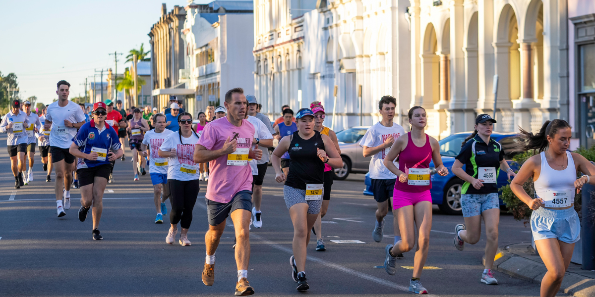 Runners participating in the Rocky River Run along the scenic Fitzroy River, with the city backdrop and other participants enjoying the scenic course