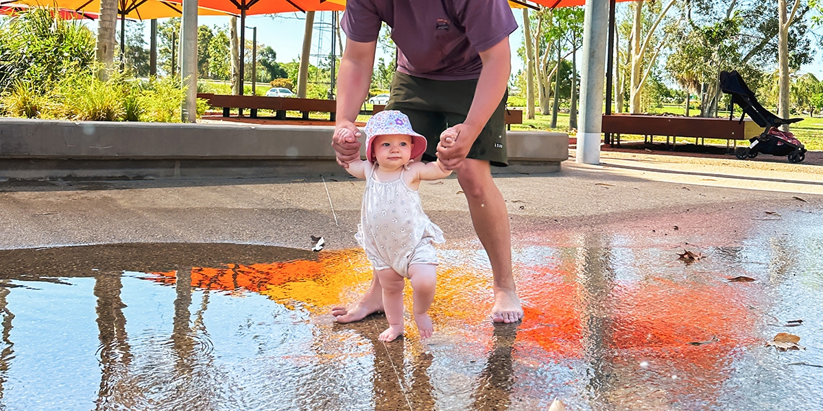 A man holding a baby having a play in a water play area