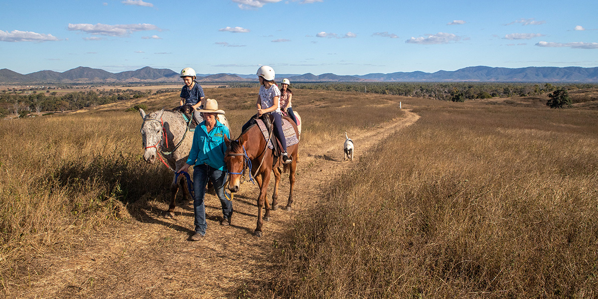 A family riding horses on a farm