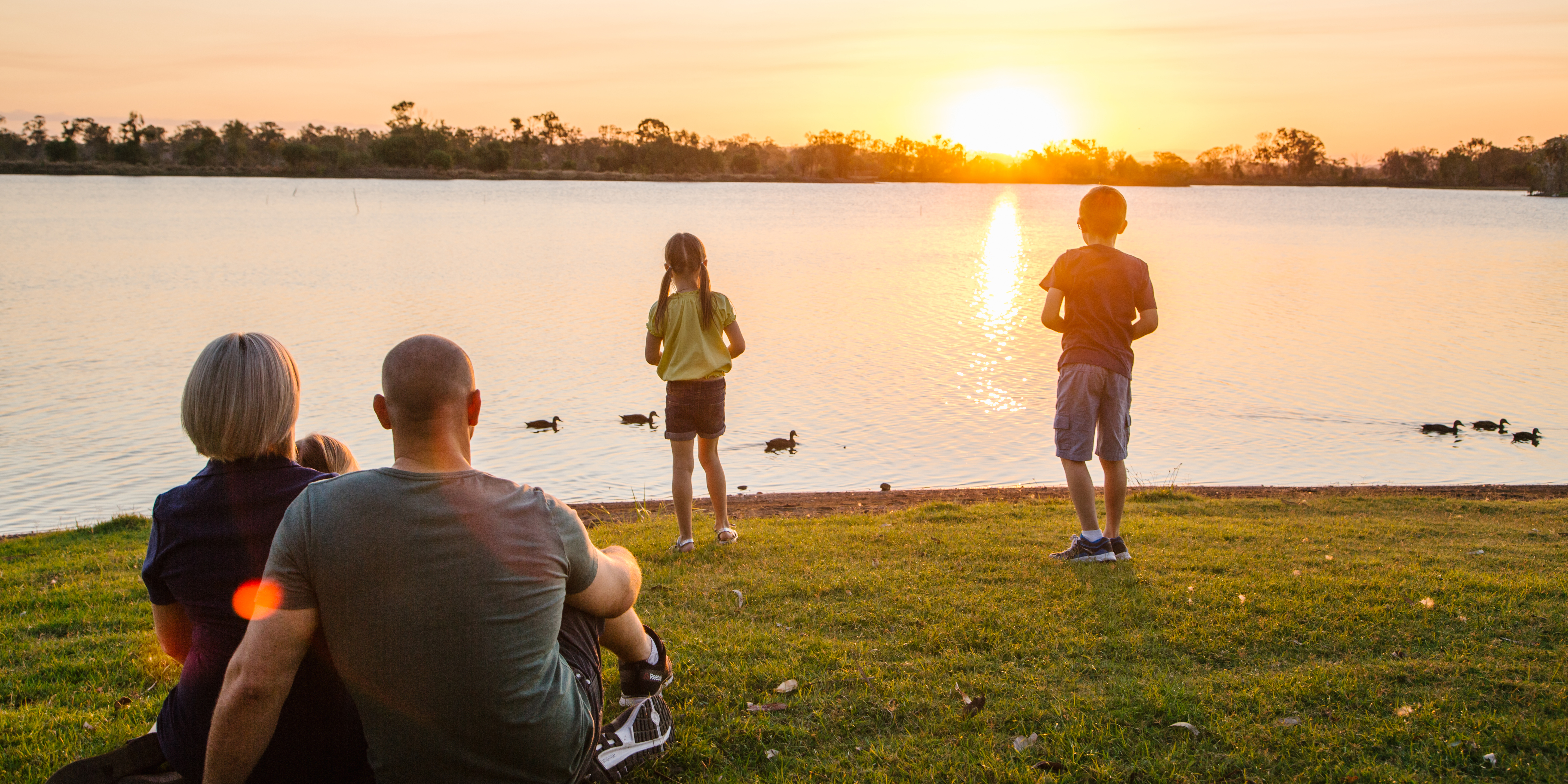 Family sitting along the banks of a lagoon on sunset