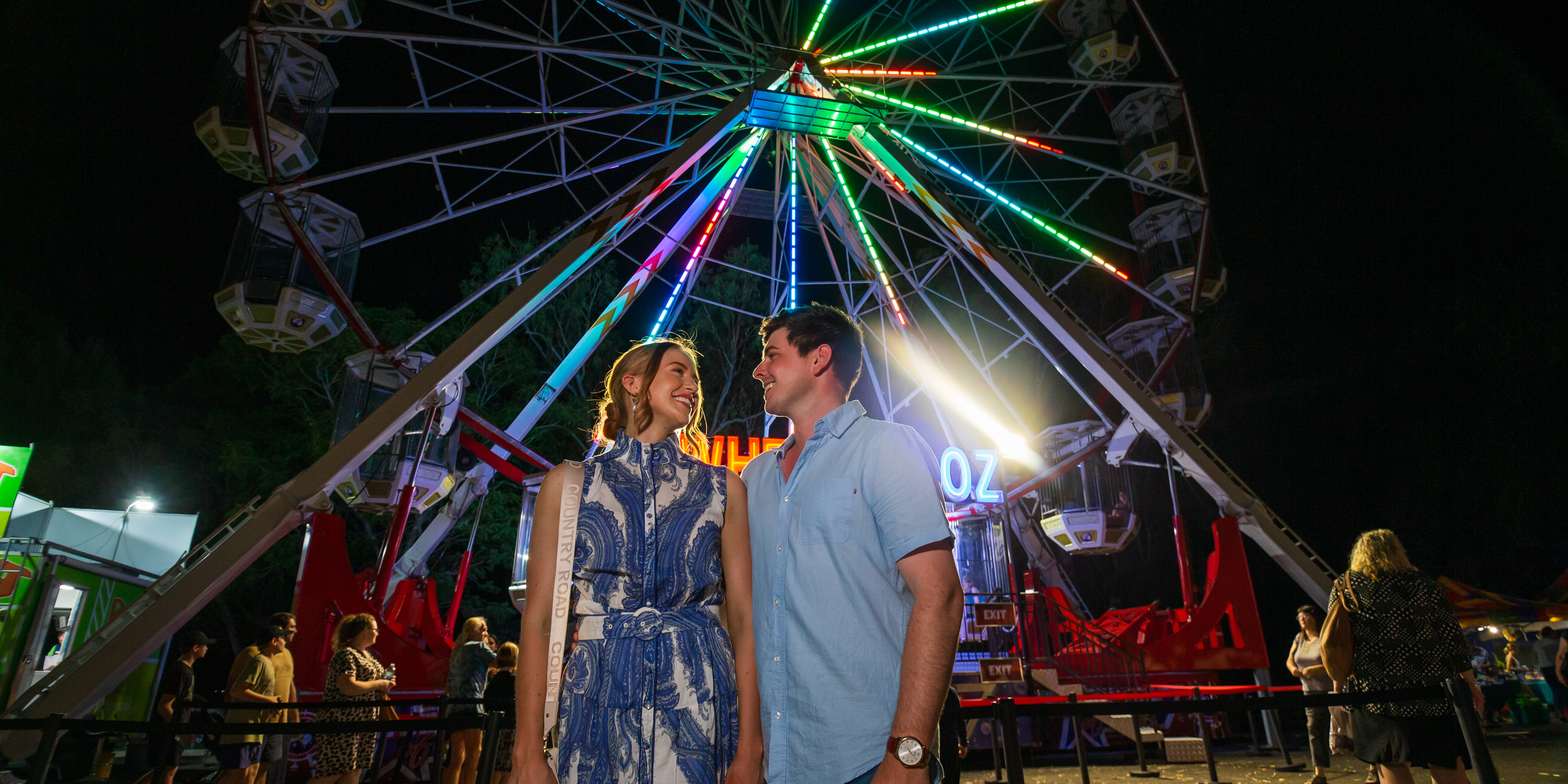 Young couple smiling with Ferris wheel in the background