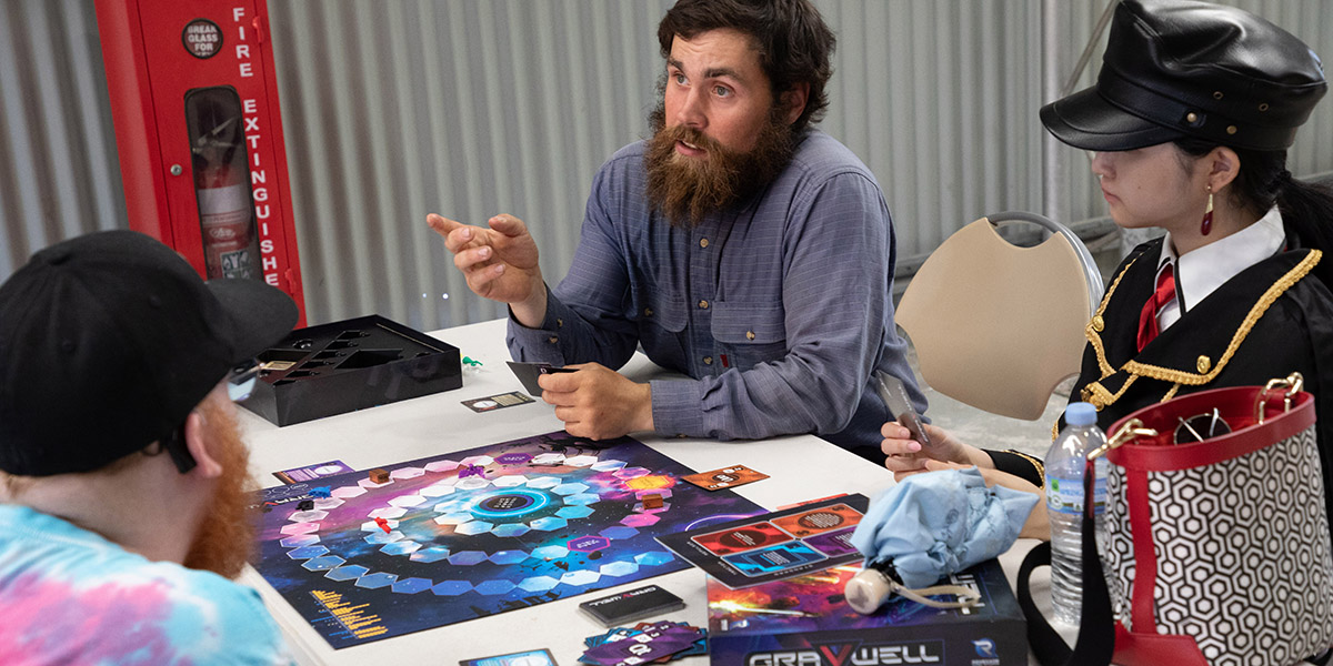 Three people sitting around a table playing a board game.