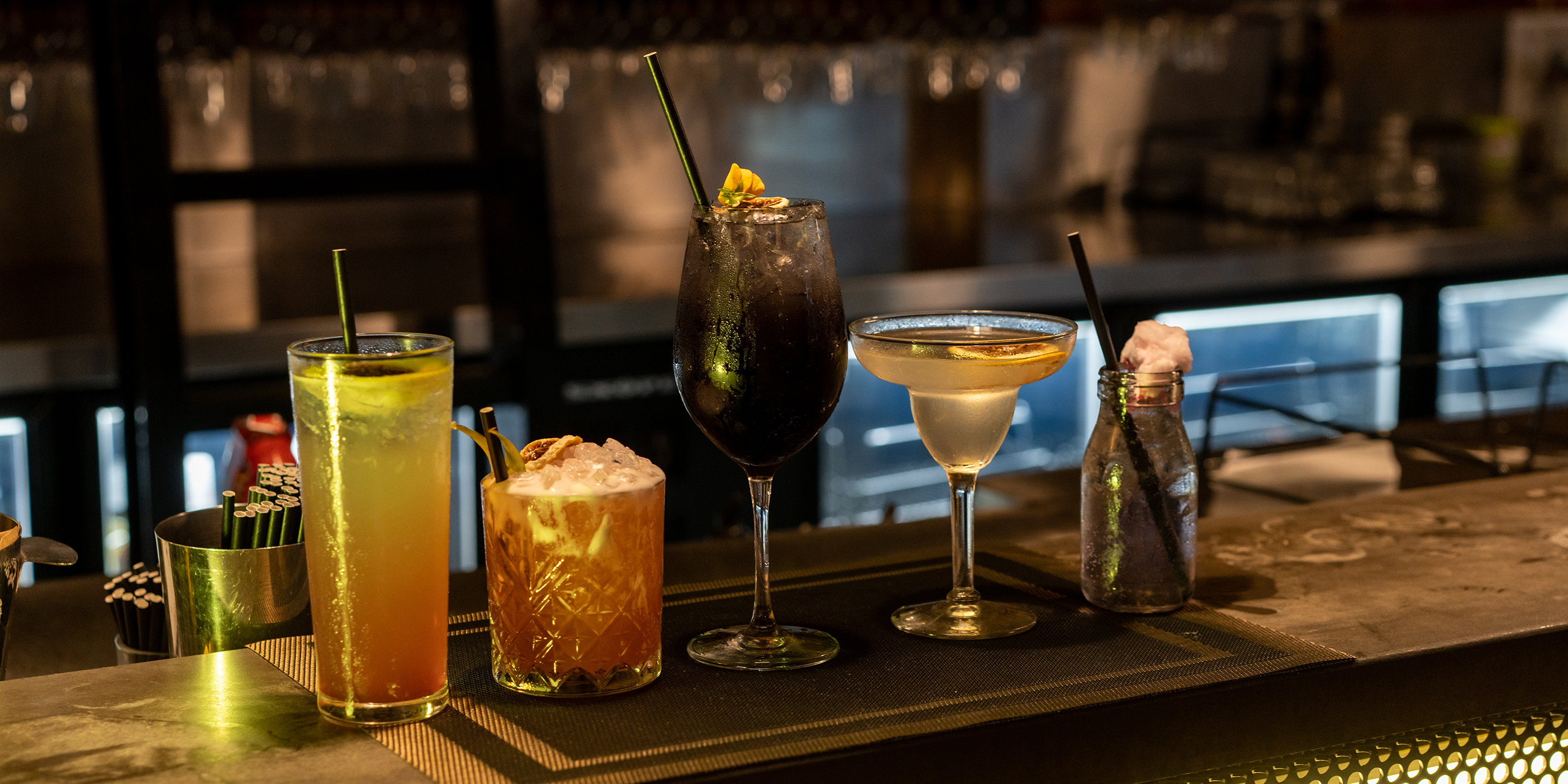 A Collection of cocktails and other spirits lined up on a bar