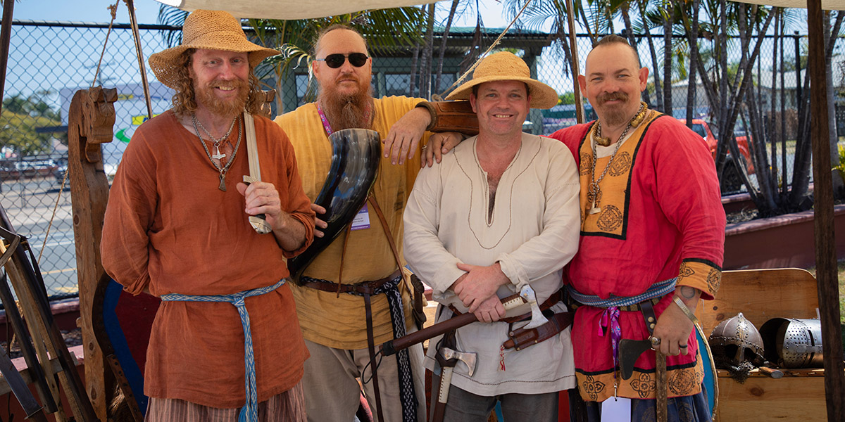 Four men dressed in medieval costume smiling at the camera.