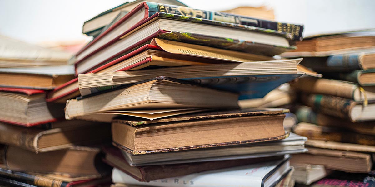 Close up of second hand books stacked high.