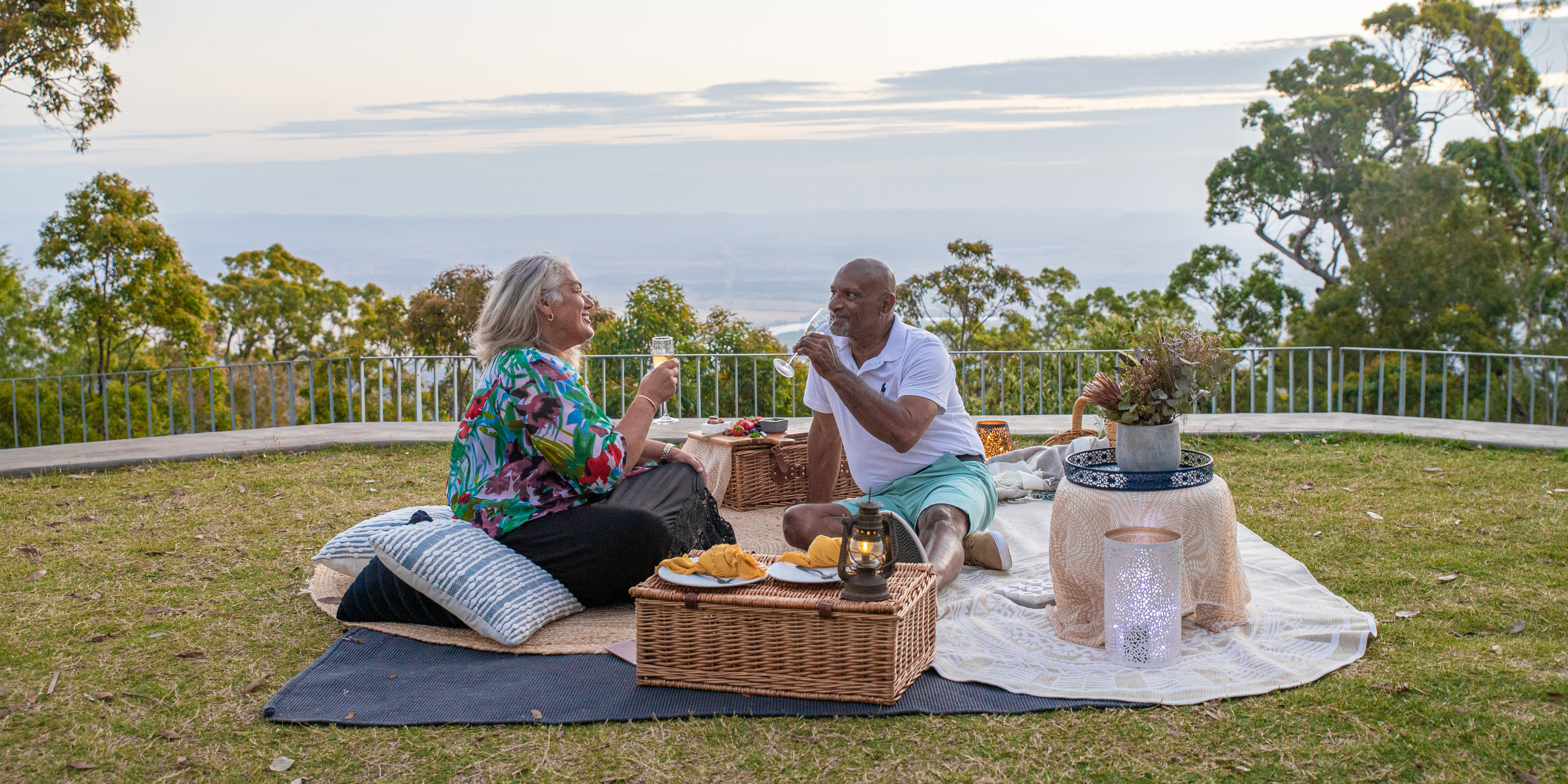 a couple enjoying a picnic at the mountain summit overlooking bush and city views of the Rockhampton region