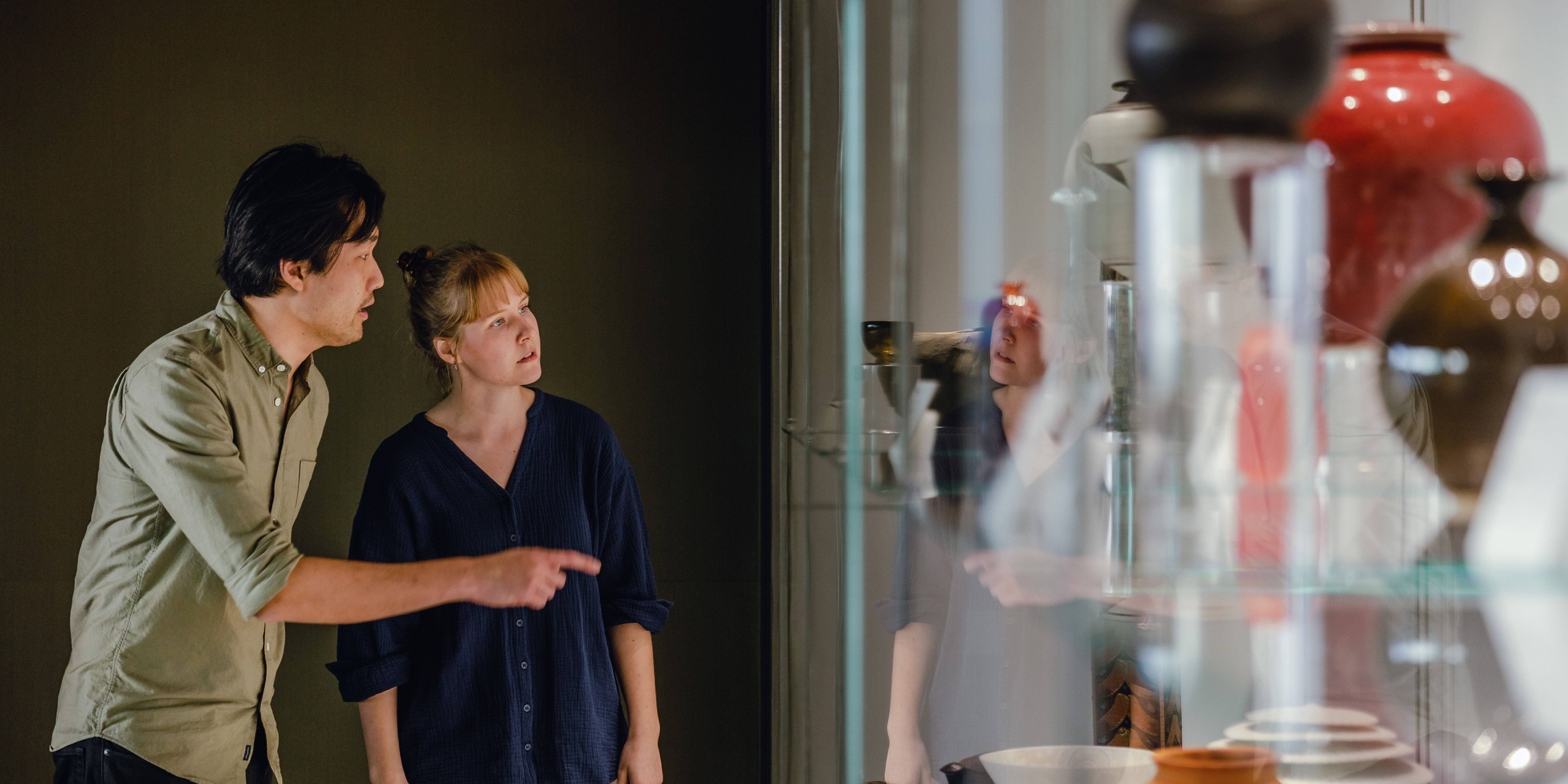 Young couple admiring sculptures through a glass cabinet