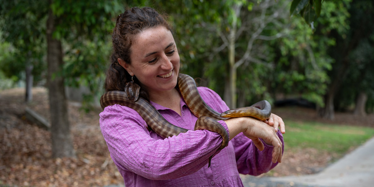 Young lady smiles as she nurses a python at Rockhampton Zoo.