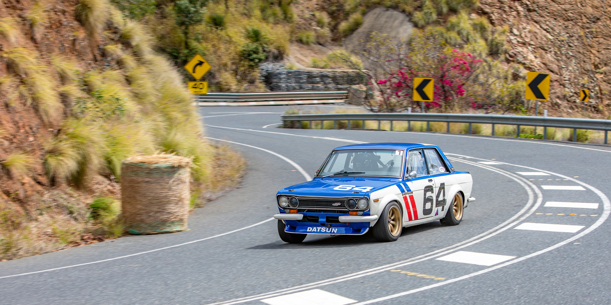 a racing car driving up a winding hill with lush green countryside