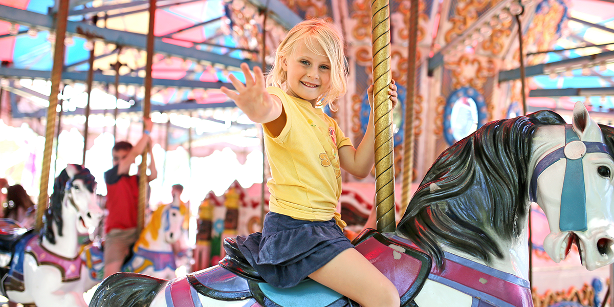 A girl riding a carousel at a show