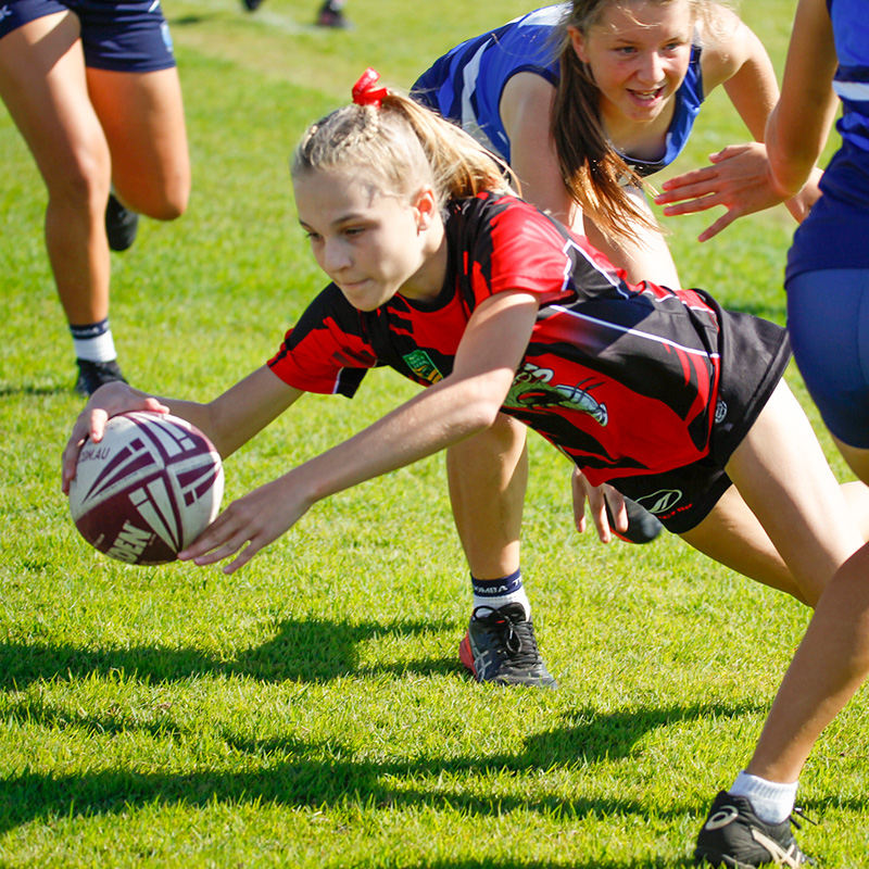 Girl with football diving on to grass