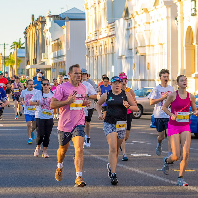 Group of runners running on road in front of historical buildings on Quay Street for Rocky River Run