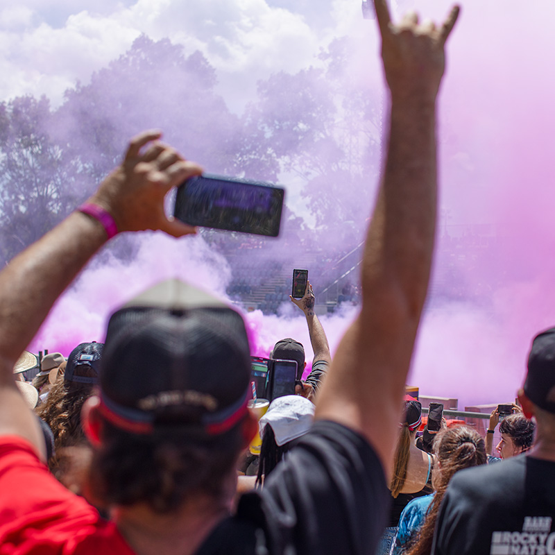 Crowd of people watching burnouts at Rockynats with phones and arms raised