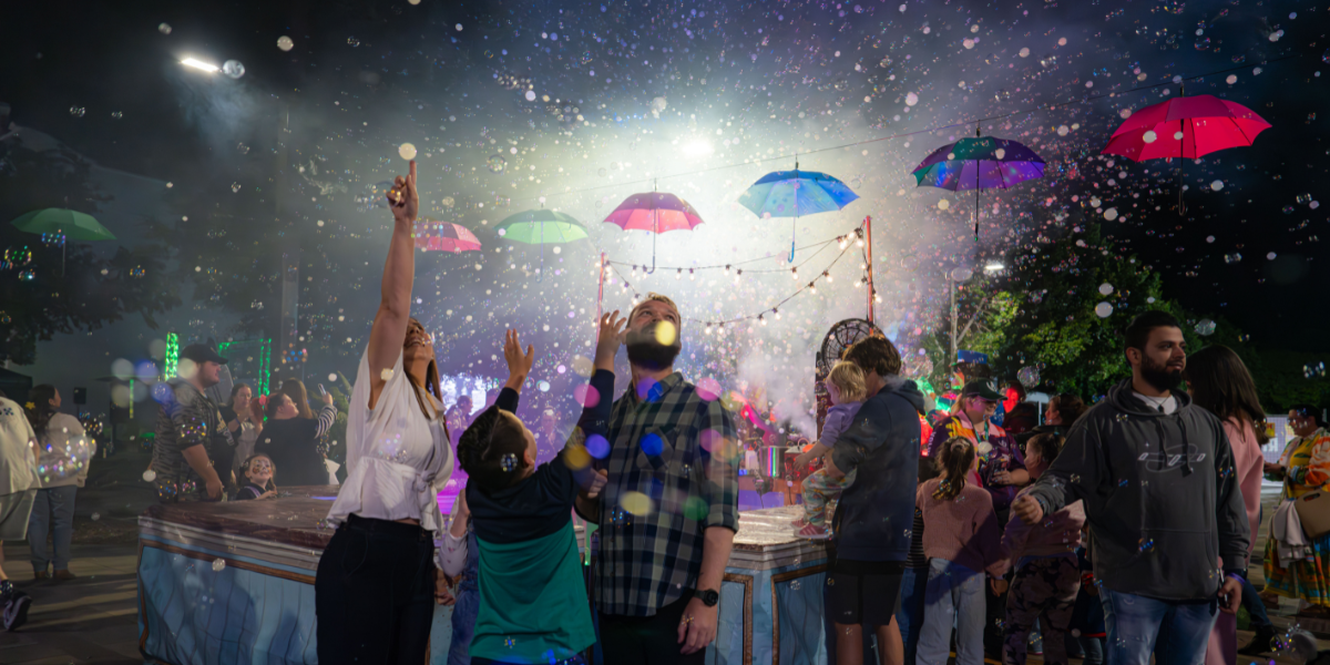 Bubbles filled with smoke, and upside down umbrellas, fill the sky around a family enjoying the Rockhampton River Festival.